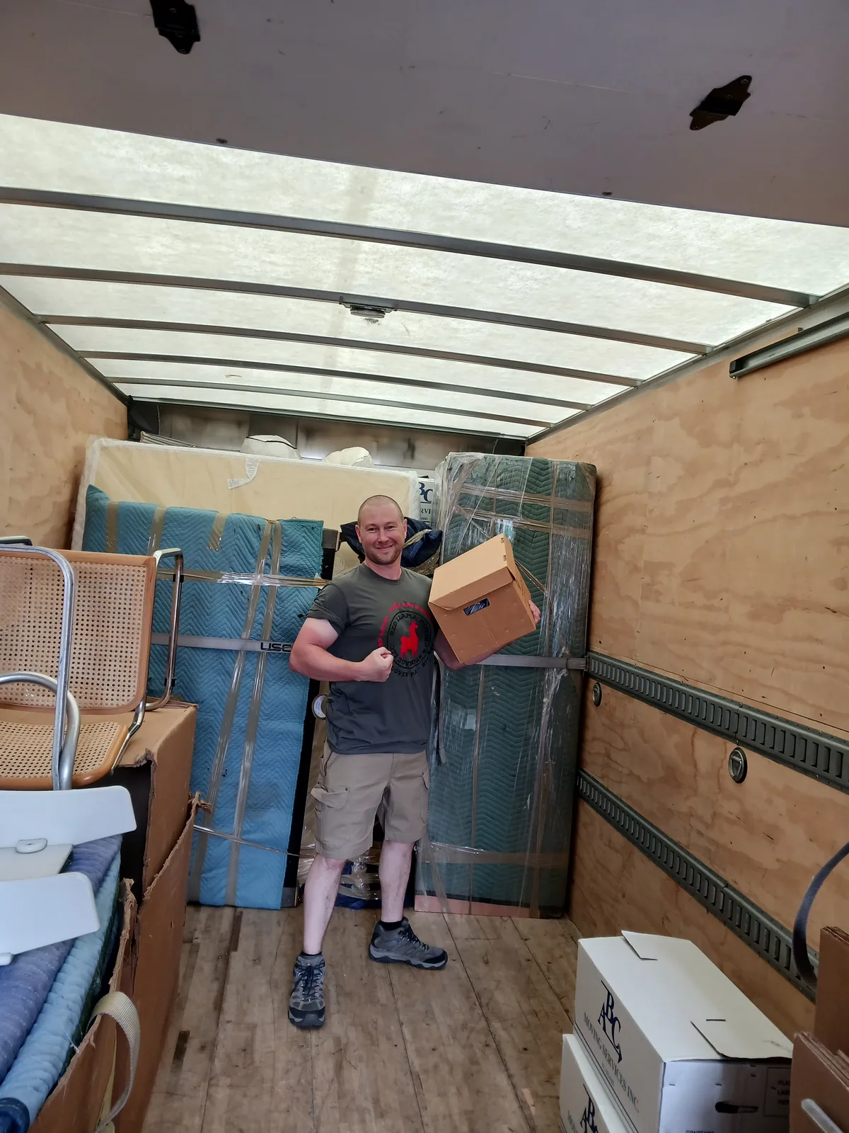 Red Llama mover organizing boxes and furniture inside a moving truck.