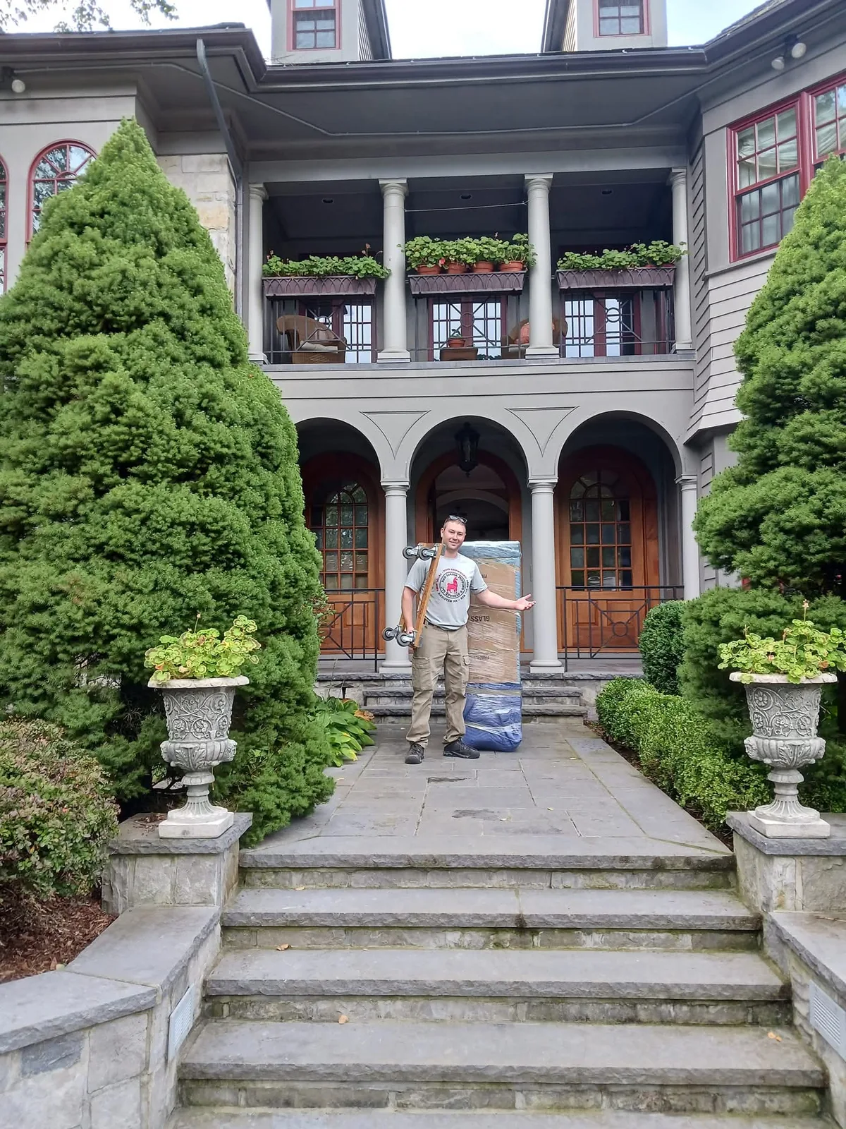Red Llama mover standing with a protected household item at an ornate home entrance.
